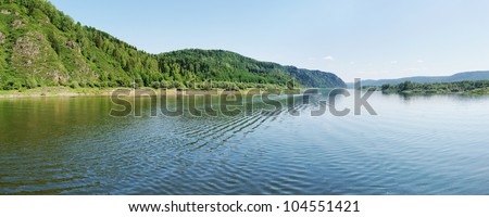 Wide panorama of a river and the forested mountains
