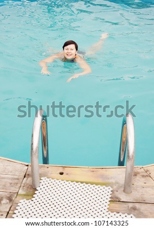 Swimming woman in an outdoor pool (focus on the woman)