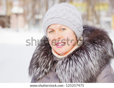 Beautiful woman in a coat with fur collar and a knitted hat