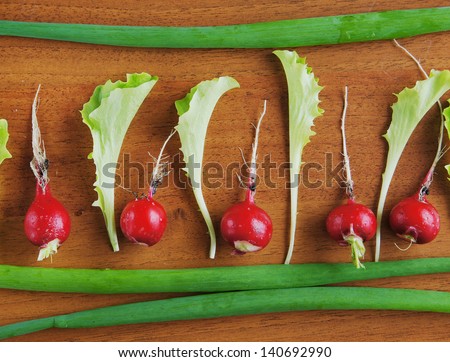 Fresh red radish and salad leaves on a wooden surface