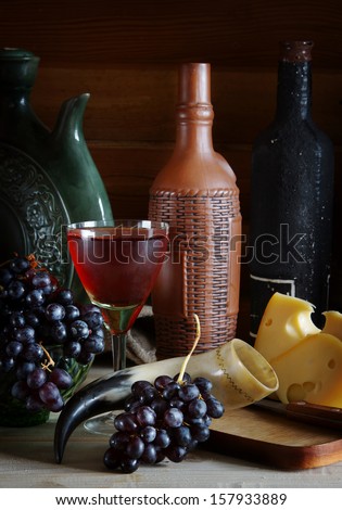 Still life with wine, grape and cheese on wooden surface