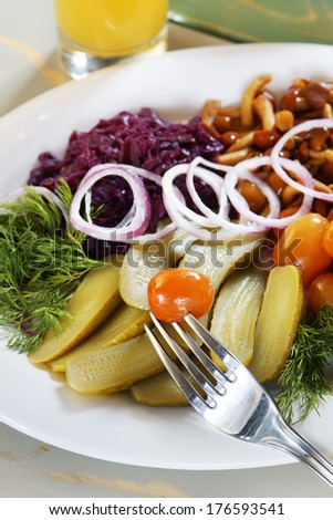 Pickled cucumbers and small tomatoes with rings of onion and mushrooms