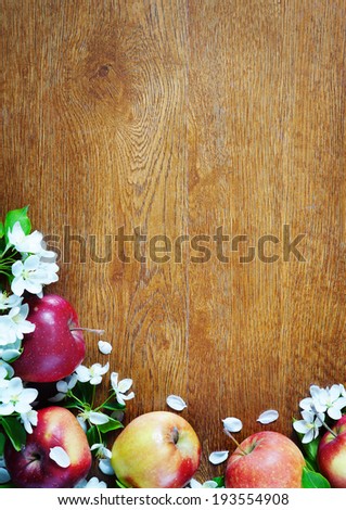 Wooden textured background with apple fruits and flowers on a bottom