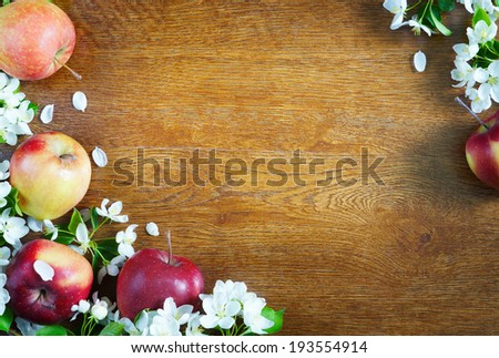 Wooden textured background with apple fruits and flowers in a corner