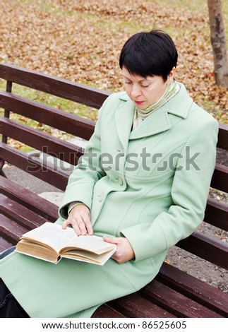 The young woman reads the book in autumn park
