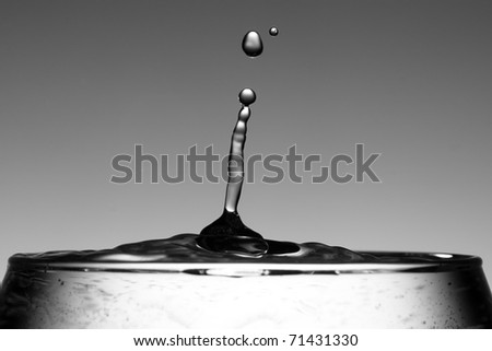 Water droplet at the top of a glass on a graduated grey background