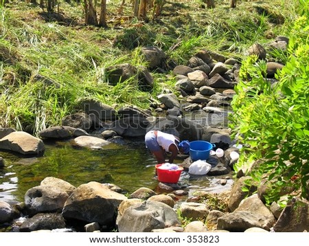 A woman washing her clothes in a small river...
