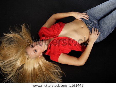Lying blond woman with a red blouse and blue jeans