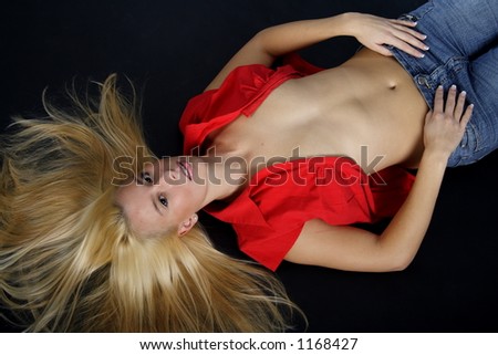 Lying blond woman with a red blouse and blue jeans