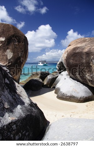 Granite rocks on a tropical beach with a boat in the background