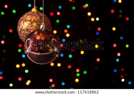 two Christmas globe hanging in the black with bright colored lights