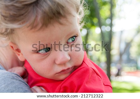 small child crying at the hands of his mother looking back