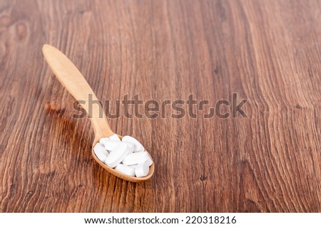 wooden spoon with pills on the background of wood