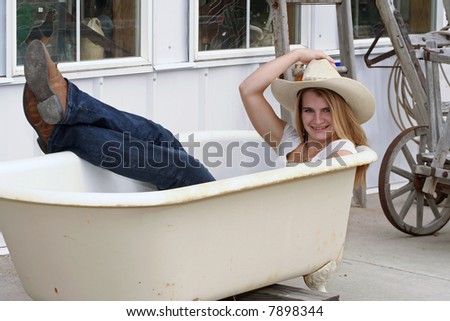 young woman taking bath in old tub with cowboy cloths