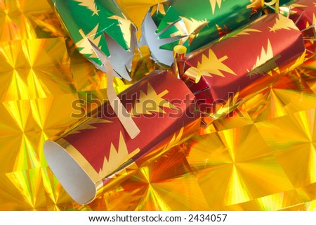 Two Christmas Crackers on a yellow party background. One of the Crackers has been pulled.