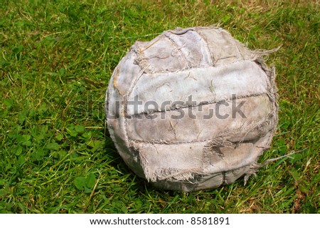 An old worn soccer football ball on grass football field with copy space on the left