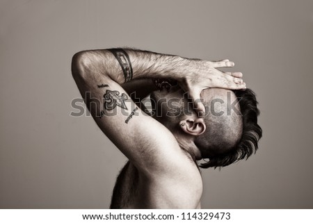 tattooed young man suffering.his hands on his face.