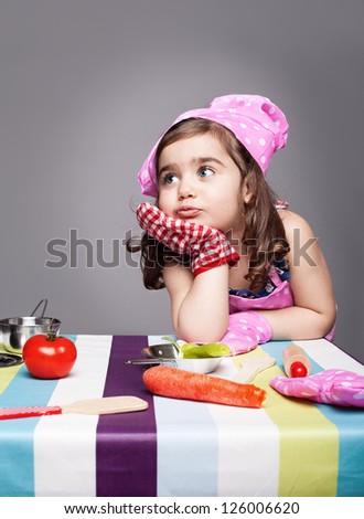 little cute chef thinking about the meal she wants to prepare on grey background