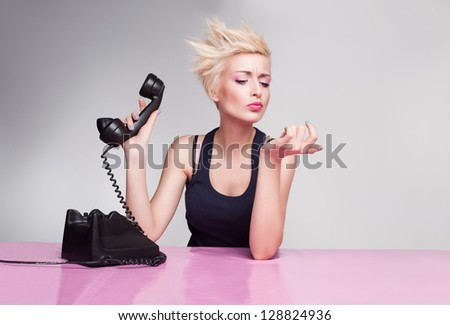 young lady with short blond hair holding handset and not listening the phone