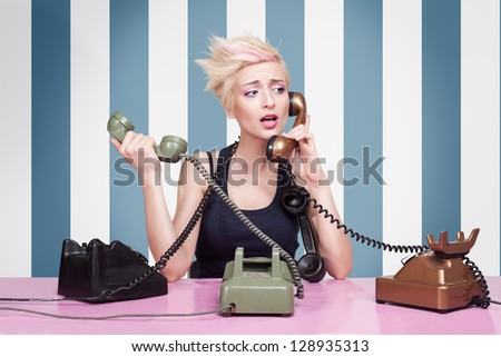 young lady trying to answer the phones on striped background