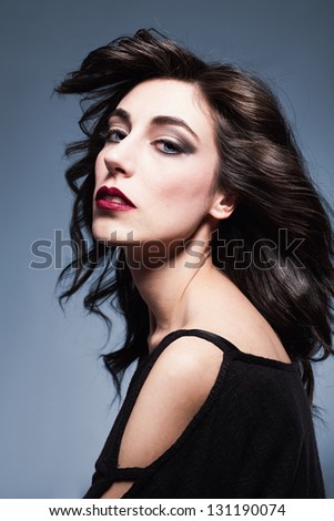 profile picture of a beautiful young lady looking at camera with her blue eyes on blue background