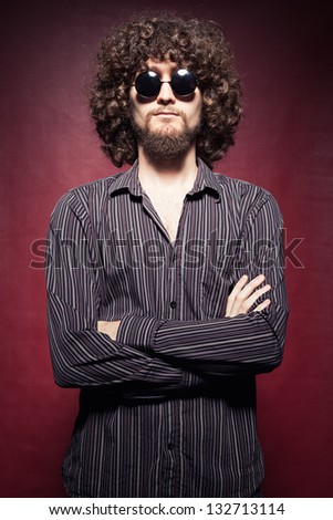 serious young man with afro style hair posing on red background
