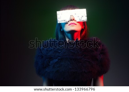 futuristic model wearing a weird glasses looking at a light source on dark background