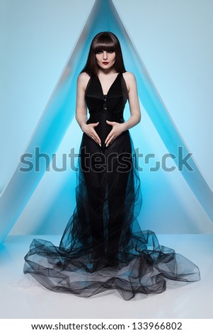 young model standing inside a triangle platform made of wood panels on blue background