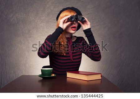 young ginger woman using binoculars found something interesting on grunge background