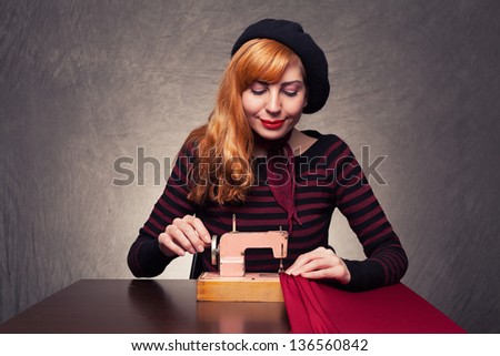 young lady using a retro sewing machine smiling and sewing on grunge background