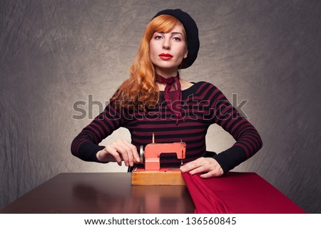 young designer with retro clothes using a retro sewing machine on grunge background