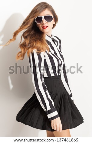 young lady turns back at camera and pose with her flying hair and flying pleated skirt on white background