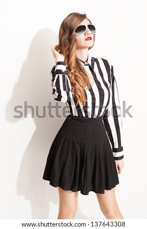 young fashion model with sunglasses and pleated skirt posing on white background