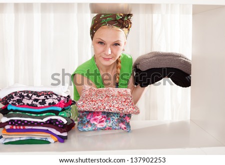 young lady removing her winterweight clothes in order to put her spring clothes in her wardrobe