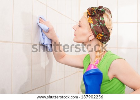 young lady with hairband cleaning the tiles with a cleaning towel