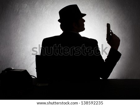 silhouette of retro style gangster holding his gun on grunge background