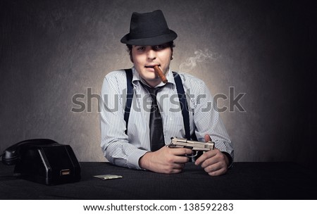 gangster holding a gun and smoking a cigar looking at camera on grunge background