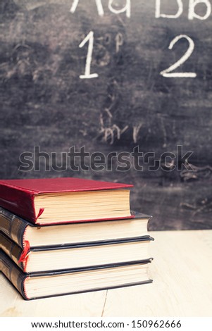 pile of old books in front of a blackboard