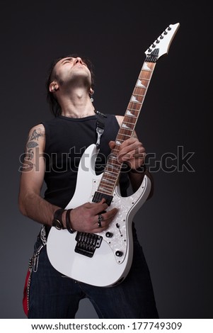 young rocker guy playing a white guitar