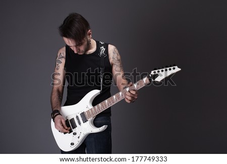 young rocker guy playing a white guitar