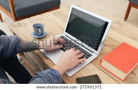 young guy with tattoed arm using a laptop