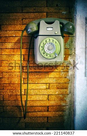 Close up shot of an old dial phone on a brick wall