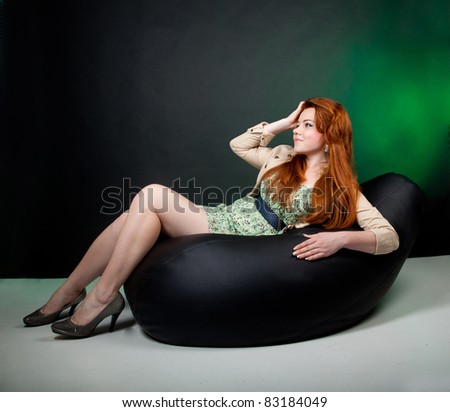 Studio shot of beautiful red haired woman laying on the sofa