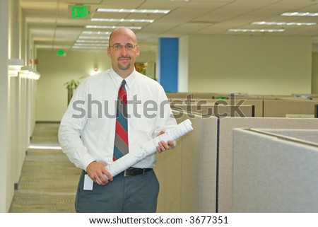 A man in his corporate office environment, on the phone and at work
