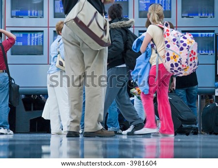 Travelers and businesspeople glance at the departure and arrival information at an airport