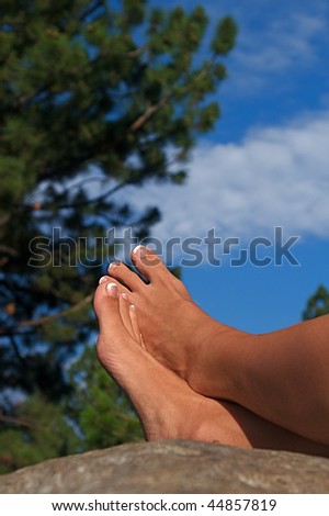 Relaxed feet of a woman laying on a boulder