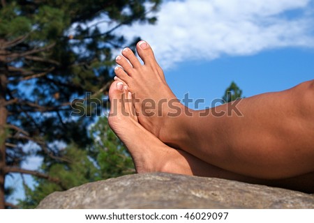 Relaxed feet of a woman laying on a boulder