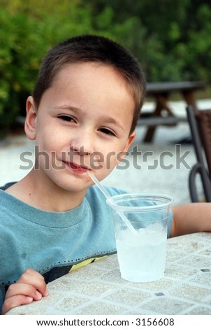 young boy enjoying a cool drink on a warm evening