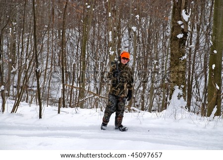 A young adult out in the woods of a sporting clays course during the winter months in the snow.
