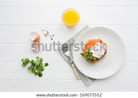 Top view of healthy breakfast with poached eggs royale (benedict), fresh orange juice and green salad